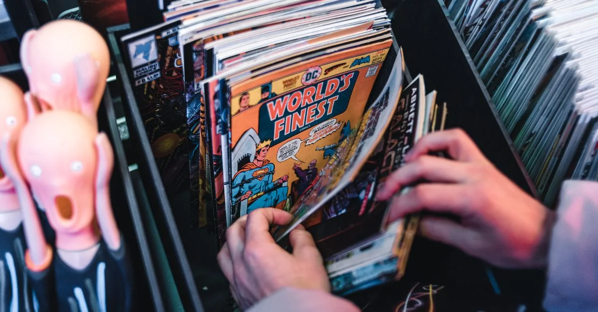 Des mains triant des bandes dessinées vintage dans une boutique, mettant l'accent sur 'World's Finest.'