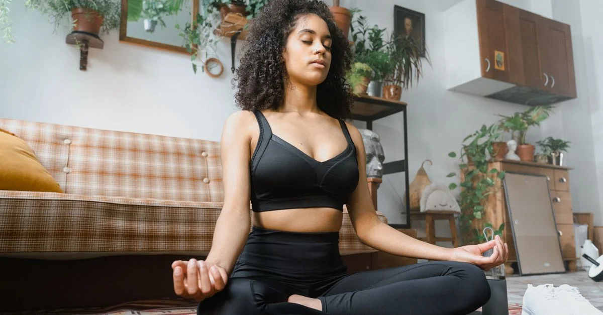 Femme calme en tenue de sport méditant à l'intérieur, promouvant un mode de vie sain.
