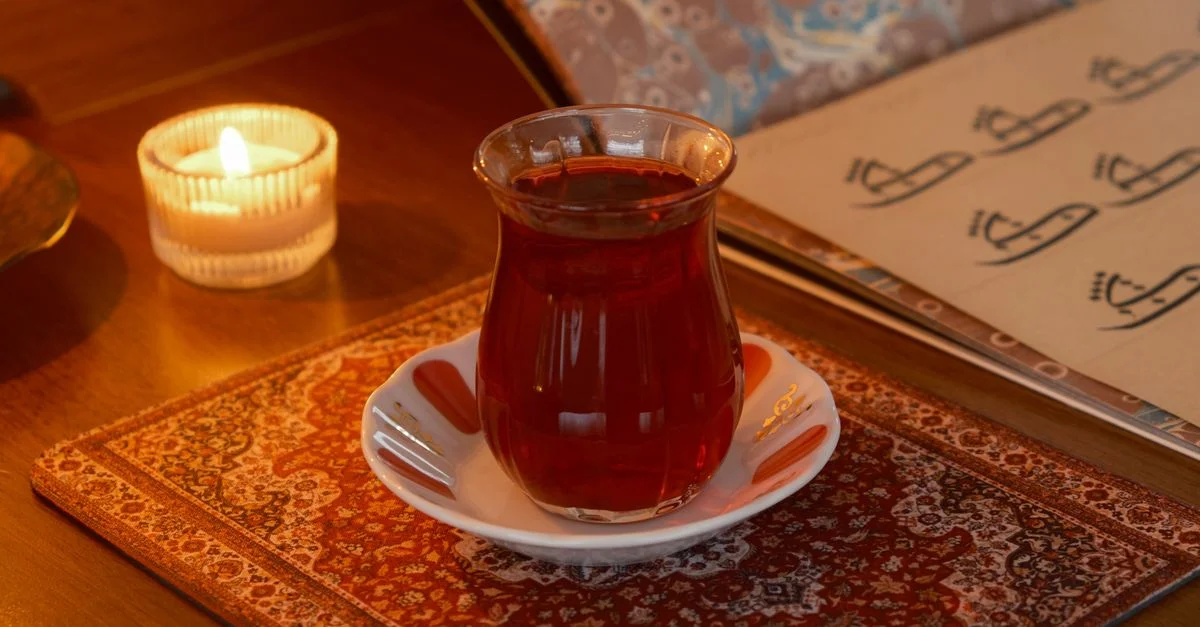 Un cadre chaleureux avec un verre à thé turc sur un tapis oriental et une douce ambiance à la lueur des bougies.