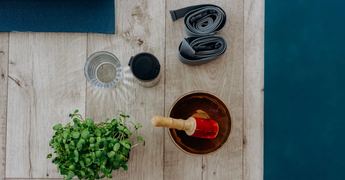 Composition à plat d'accessoires de yoga et de méditation comprenant un tapis, des sangles et un bol chantant.