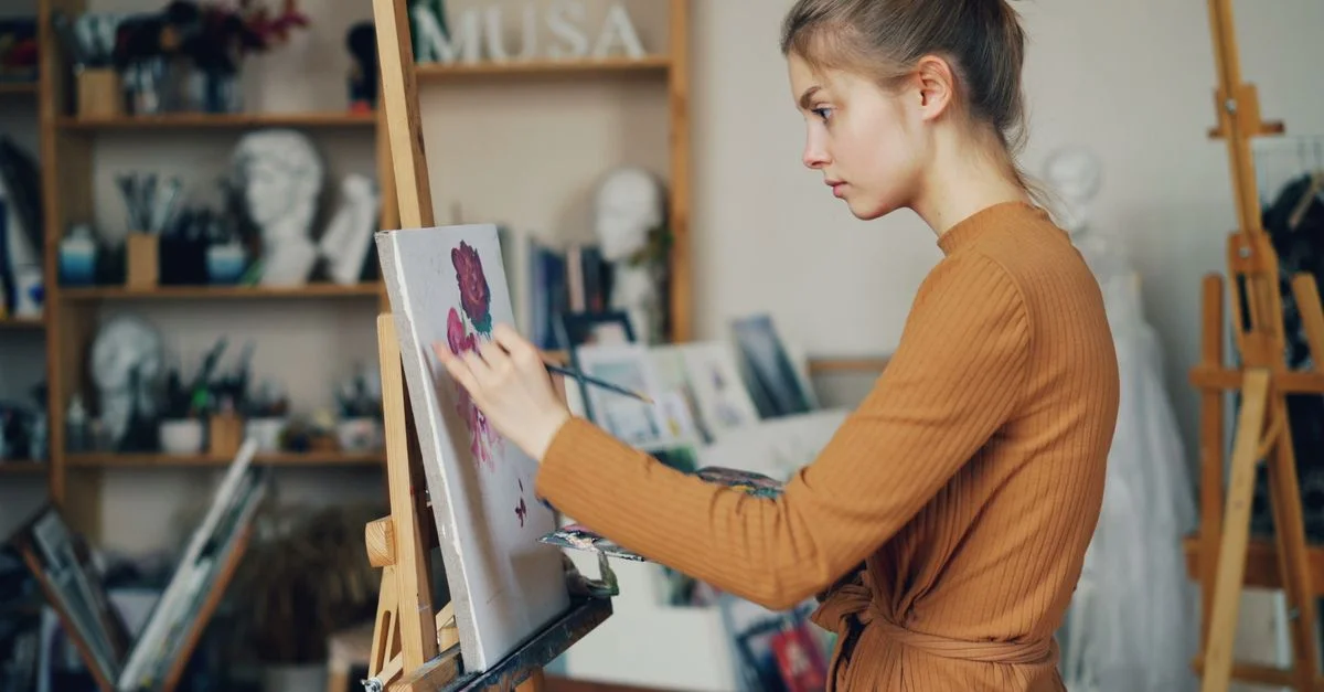 Jeune femme artiste peignant sur une toile dans un environnement de studio d'art intérieur.